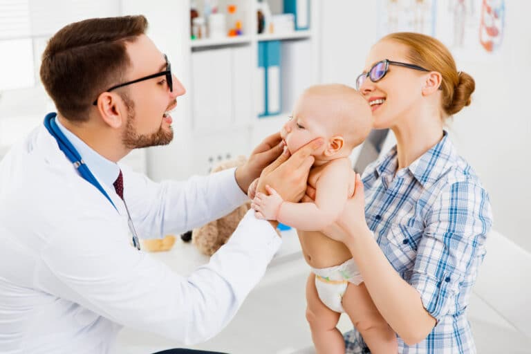 Mother holding her toddler during a pediatrician visit, highlighting a routine checkup and comprehensive child health assessment