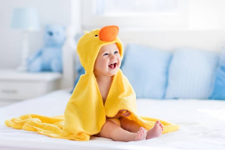A baby in a yellow hooded bath towel