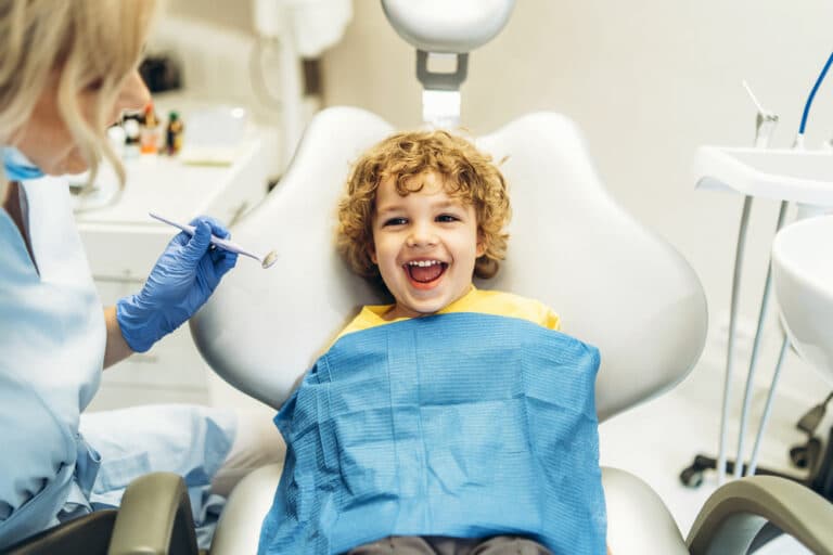 Young child laughs at the dentist office, excited by the fun care he receives.